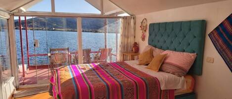 A bedroom with a bed, a window, and a view of the water.