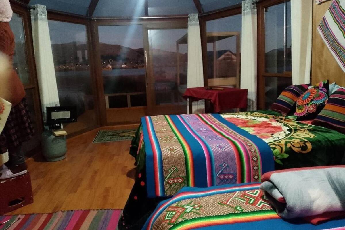 Ein Zimmer mit einem großen Bett, einem kleinen Tisch und Blick durch eine Glastür.
