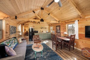 Interior de una cabaña de madera con comedor, cocina y sala de estar.