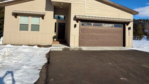 Ein zweistöckiges Haus mit Garage, Eingangstür und einer kleinen Veranda.