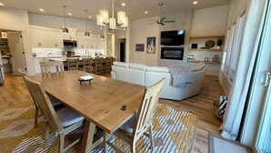 Eine moderne Küche mit weißen Schränken, einem Esstisch mit Stühlen, einer Couch und einem Deckenventilator.