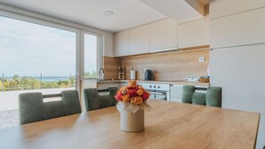 A modern kitchen with a wooden countertop, a sink, and a view of the sea.