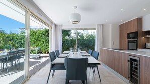A modern kitchen with a dining area, large windows, and a view of greenery. - 3-Br Garden-Level Apartment – Near Beach with Parking (Cannes)
