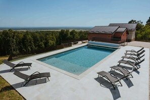 A rectangular swimming pool with a clear blue water surface, surrounded by a concrete deck. There are six lounge chairs arranged around the pool. - Stay among vineyards with views of Lonjsko Polje (Kutina)