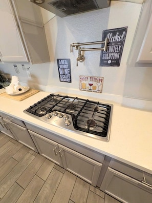 A kitchen with a gas stove, cabinets, and a wall-mounted sign that reads 'Alcohol is the infinitely best solution.' - Spacious 4BR w/ 3xGarage, Single-Story Comfort & Family-Pet Friendly 5x TV's 3 Bath 1/2 acre (Las Vegas)