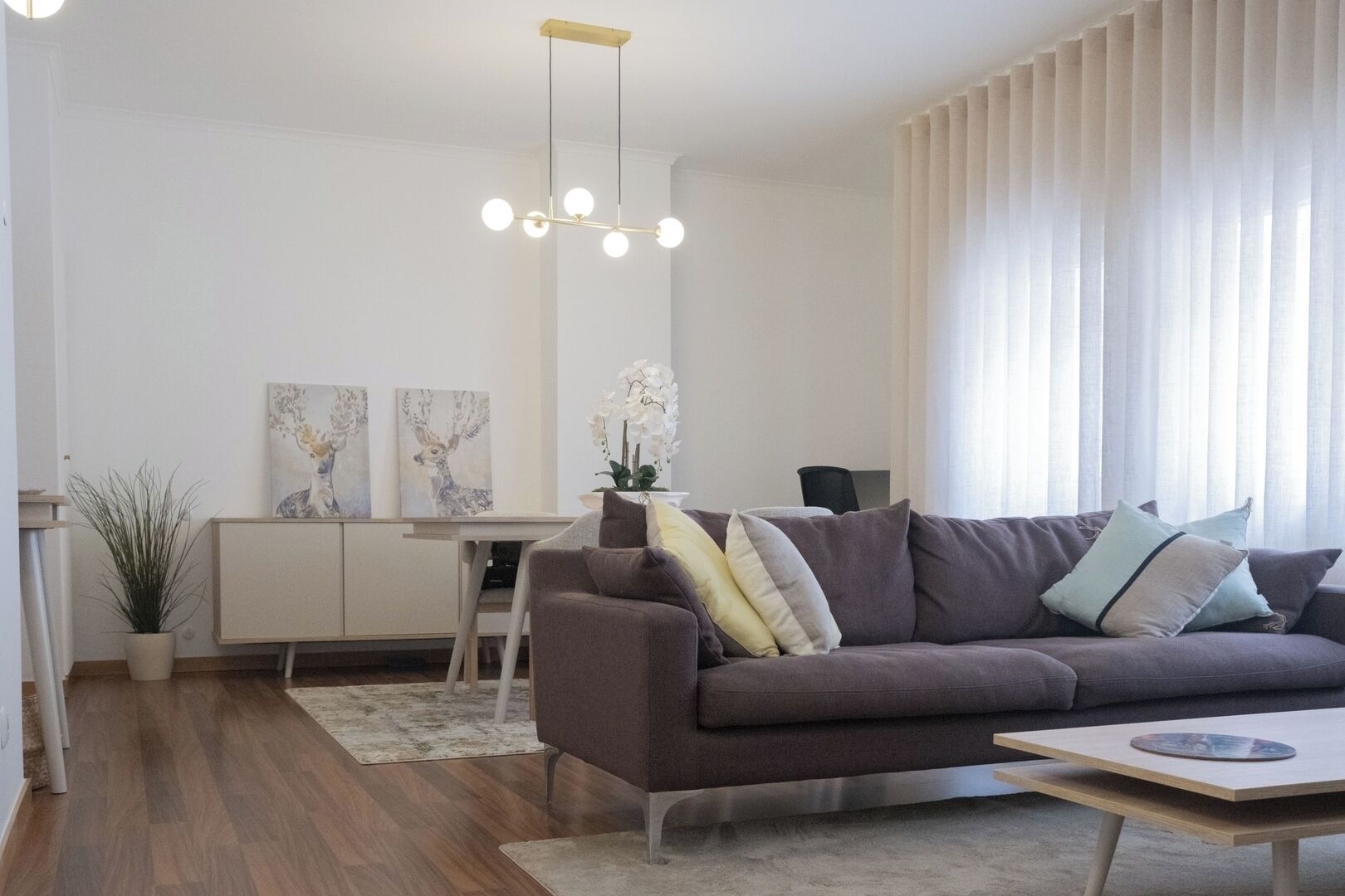 En moderne stue med sofa, sofabord og et spiseområde med bord og stole.
