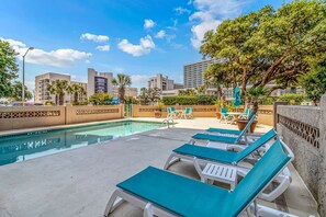 A pool area with lounge chairs and a view of the cityscape. - Ocean Dunes Tower I - Unit 4054 (Myrtle Beach)