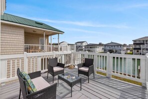 A deck with wicker furniture and a view of neighboring houses. - Blushing Mermaid (North Myrtle Beach)