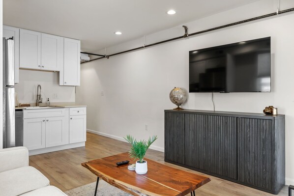 Una sala moderna con una mesa de centro de madera, un globo terráqueo y un televisor de pantalla plana sobre un mueble de madera oscura.