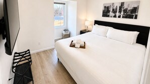 Een hotelkamer met een bed, een televisie, een lamp, een schilderij en een raam.