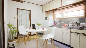 A compact kitchen with white cabinets, a microwave, a sink, and a dining area with a table and chairs. - [Sapporo Private House ] 8-minute walk from subway station and airport bus stop (Sapporo)