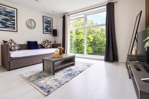 A modern living room with a sofa, coffee table, and a large window with curtains. - Flat in Manchester – Dudley's Dove (Manchester)