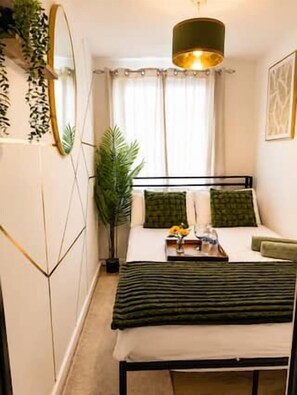 Un dormitorio con cama, mesita de noche y lámpara colgante.
