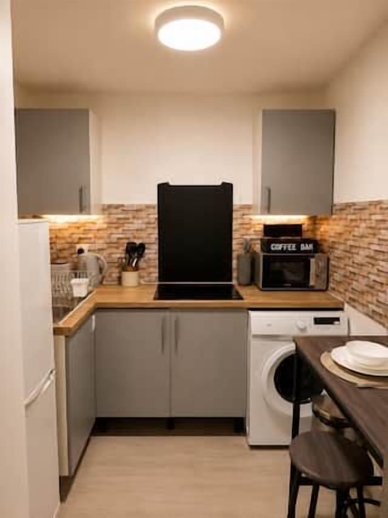 A compact kitchen with a washing machine, a coffee machine, and a microwave.