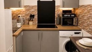 Ett kompakt kök med tvättmaskin, kaffebryggare och mikrovågsugn.