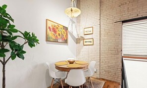 Un comedor con una mesa redonda, sillas blancas y una planta en maceta.