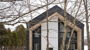 Ett modernt hus med en stor veranda, en öppen spis och en snötäckt trädgård.