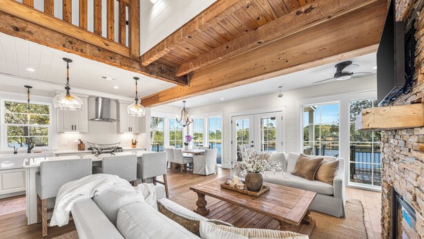 A spacious living area with a wooden ceiling, a fireplace, and a view of the outdoors. - Bella Vista & Coastal Chateau: Lakefront Retreat with Dock, Kayaks, Bikes & Fire Pit (Seacrest)