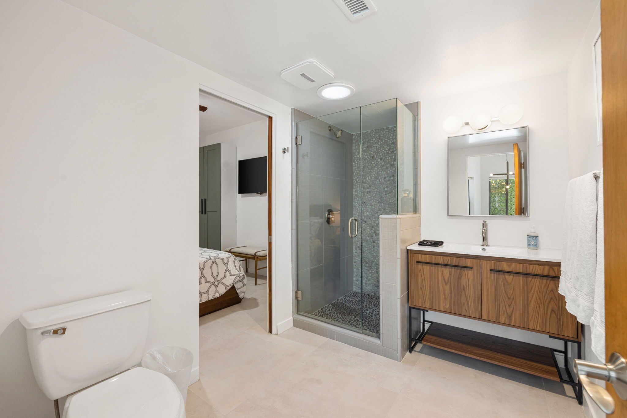 Une salle de bain moderne avec une douche à parois de verre, un meuble-lavabo en bois et des toilettes blanches.