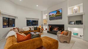 Uma sala de estar moderna com lareira, televisão de tela plana e um espaço de estar confortável.