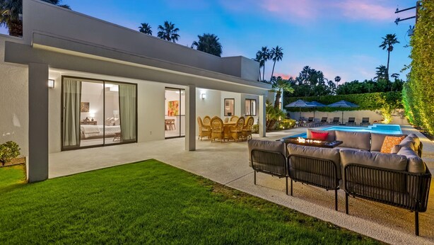 Uma casa moderna com piscina, área de estar externa e gramado bem cuidado.