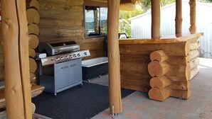 A wooden cabin with a grill, a sink, and a window. - Stunning Tidal Waters Loglodge (Tolaga Bay)