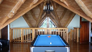 A pool table in a room with wooden beams and a railing. - Stunning Tidal Waters Loglodge (Tolaga Bay)