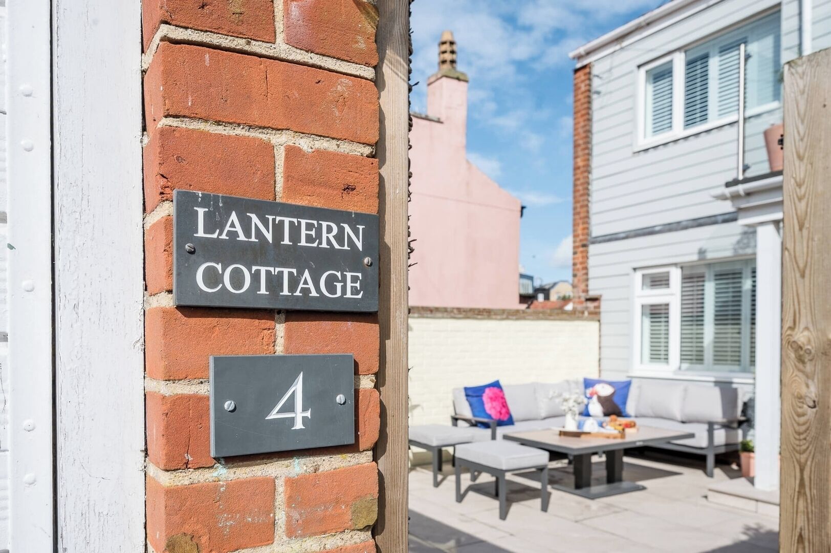 Eine Ziegelwand mit einem Schild 'Lantern Cottage' und der Hausnummer 4.