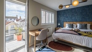 Une chambre à coucher avec un lit, une table de chevet, une lampe et une vue sur l’extérieur.