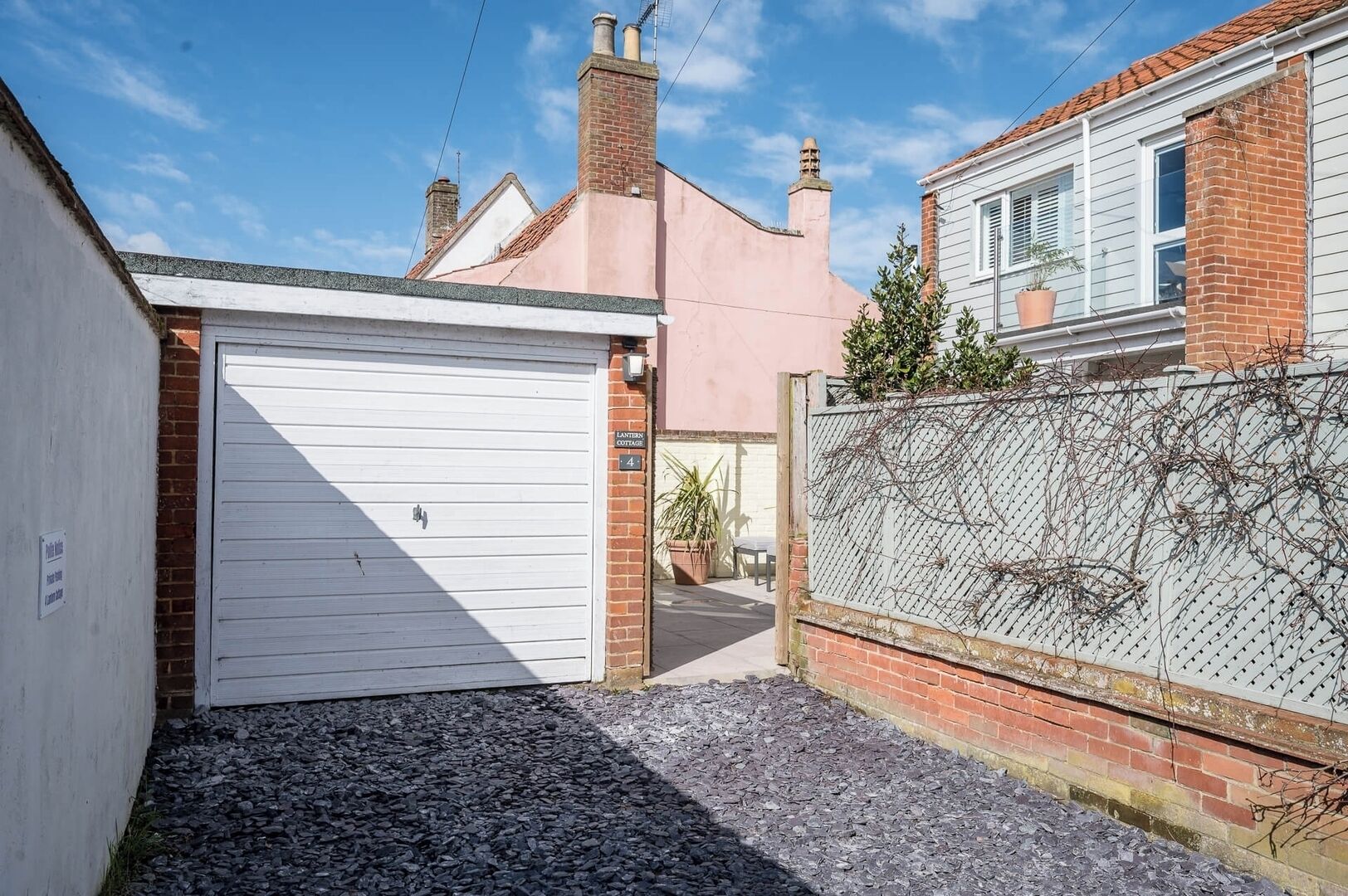 A residential property with a white garage door, a brick wall with a climbing plant, and a visible house number '4'.
