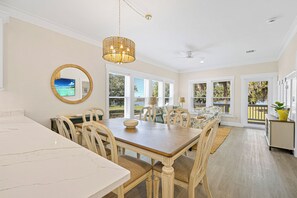 Un coin repas avec une table en marbre, des chaises en bois et un lustre.