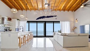 A modern kitchen with a large island, bar stools, and a view of the sea through large windows. - NEW! Oceanfront Lux Villa w/ Private Infinity Pool, King Suites, Dock to Ocean (Punta Blanca)