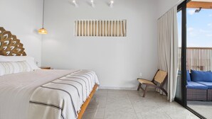 A bedroom with a bed, a chair, a window with curtains, and a view of the outside. - NEW! Oceanfront Lux Villa w/ Private Infinity Pool, King Suites, Dock to Ocean (Punta Blanca)