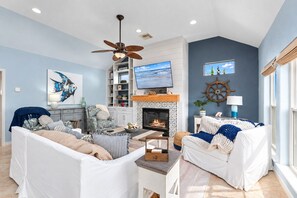 Un salon avec une cheminée, un ventilateur de plafond et une grande fenêtre.