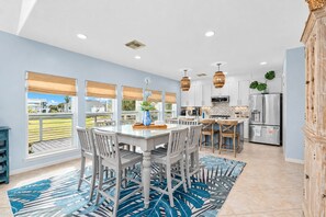 A modern kitchen with a dining area, large windows, and a view of the outdoors. - Modern 3BR Galveston with Fire Pit & Private Pool & Jacuzzi | Mins to the Beach (Galveston)