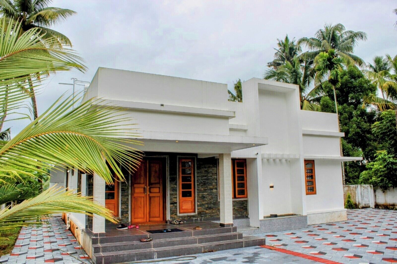 A modern two-story house with a flat roof, a front porch, and a stone facade.