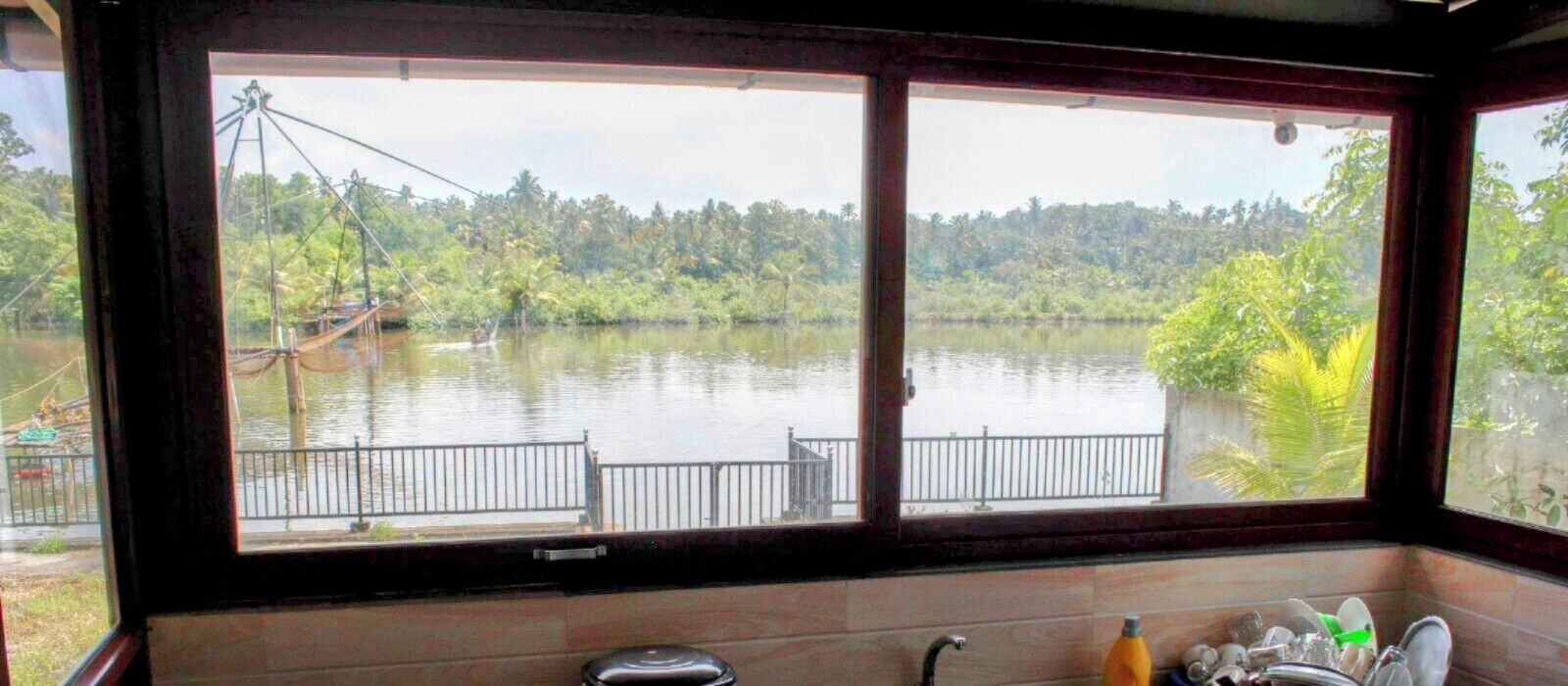 A room with a large window overlooking a lake, a metal railing outside, and a tiled wall.