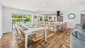 Una cucina moderna con mobili bianchi, un'isola centrale e un'area pranzo con tavolo e sedie bianche.