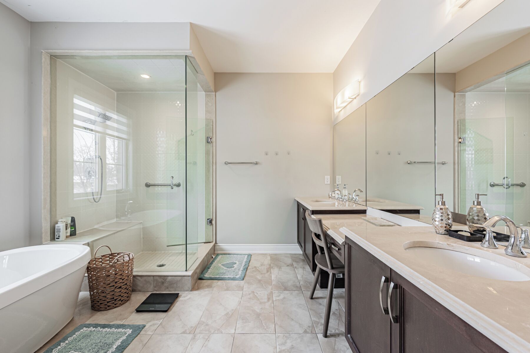 A modern bathroom with a glass-enclosed shower, a bathtub, and a vanity with a large mirror.
