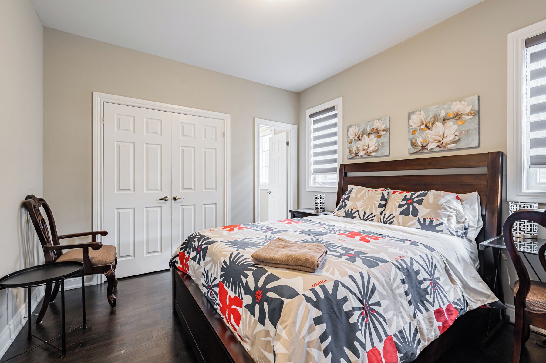 A bedroom with a bed, a chair, a nightstand, and a door.