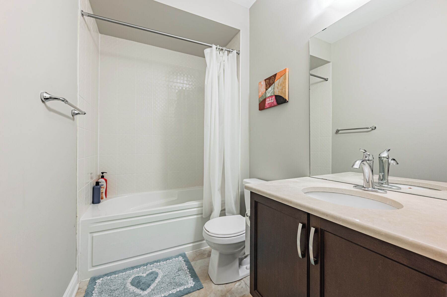 Un baño con ducha, inodoro y tocador con espejo.