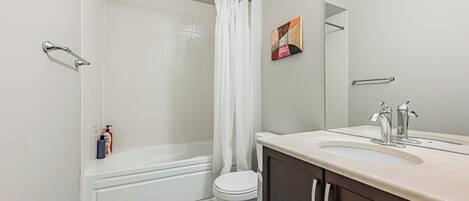 Un baño con ducha, inodoro y tocador con espejo.