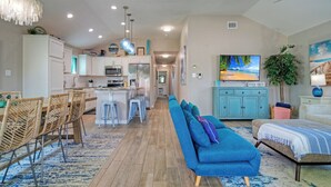 Une cuisine moderne avec des meubles blancs, un îlot central et un coin repas doté de chaises en osier.