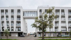 Un edificio moderno con un atrio central, varios balcones y un árbol en primer plano.