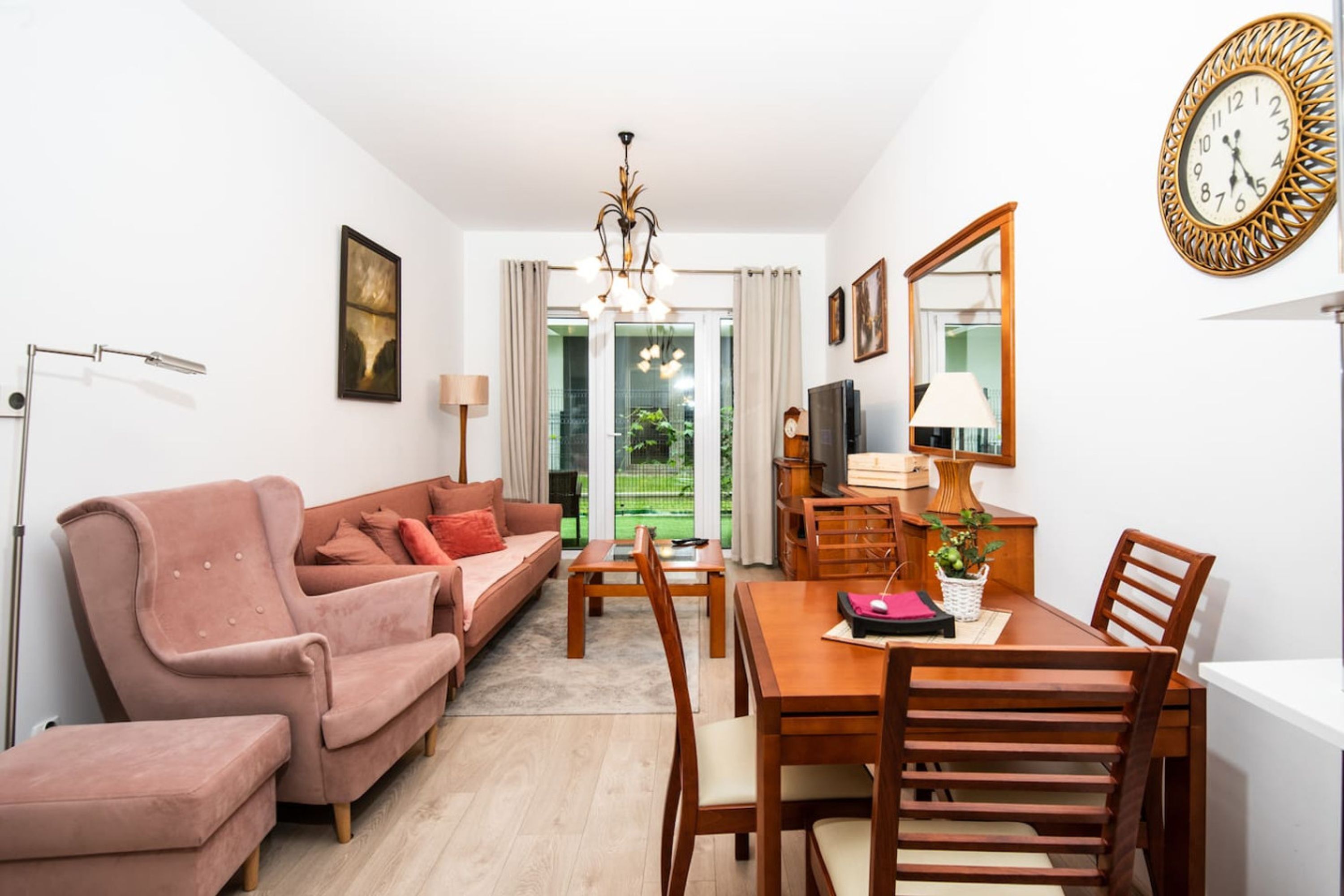 Ein modernes Wohnzimmer mit einer Couch, einem Esstisch, Stühlen, einem Fernseher und einer Deckenleuchte.
