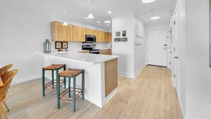 Una cocina moderna con una isla central, armarios de madera y una zona de comedor con taburetes de bar.