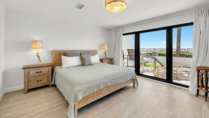 Un dormitorio con cama, mesitas de noche, ventana con vistas y lámpara de techo.