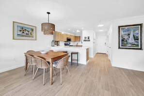 A modern kitchen with wooden cabinets, a central island, and pendant lighting. - Aegean 119 ocean views near beach (Destin)