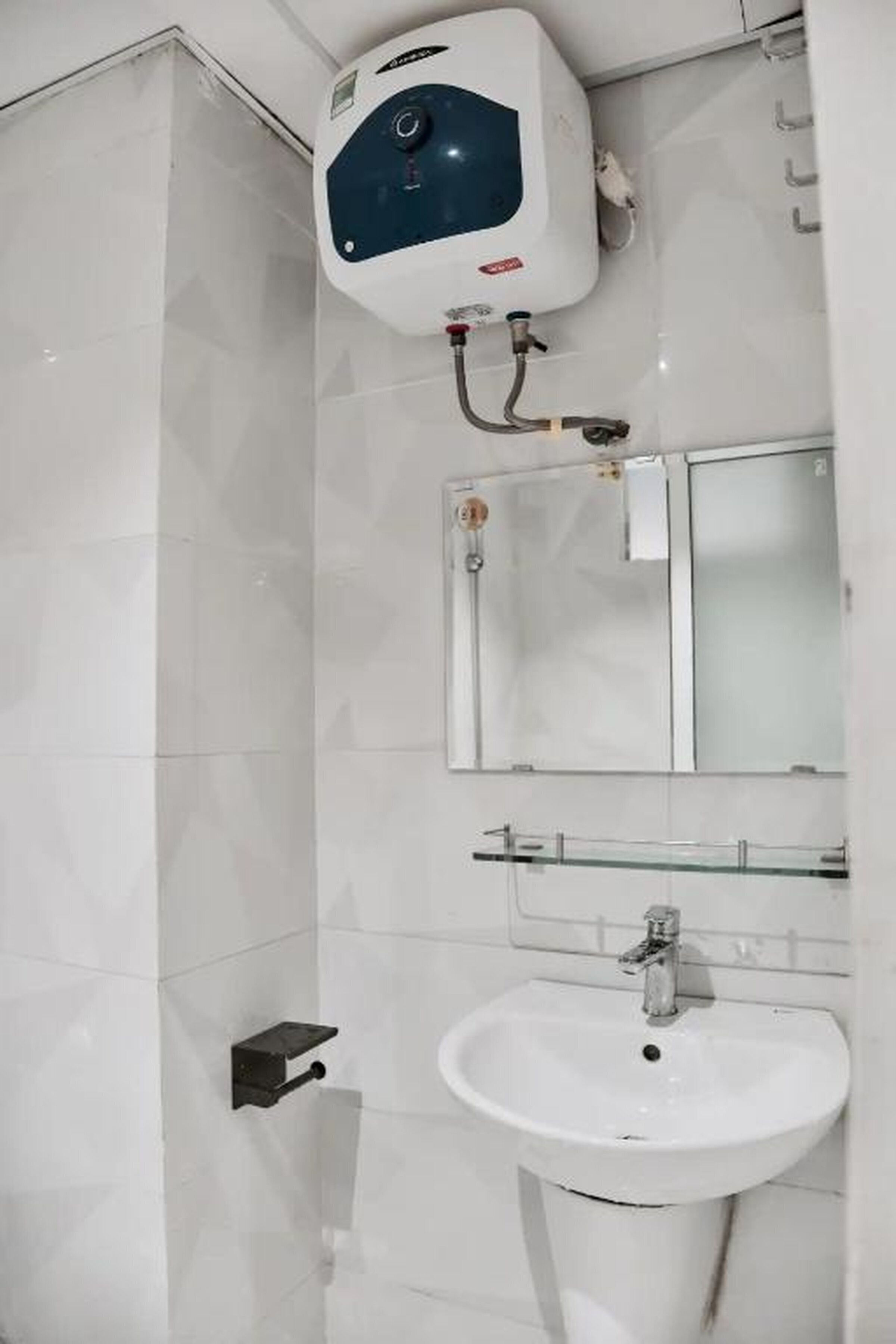 Ein Badezimmer mit weißem Waschbecken, einem Spiegel und einem Wandheizkörper.