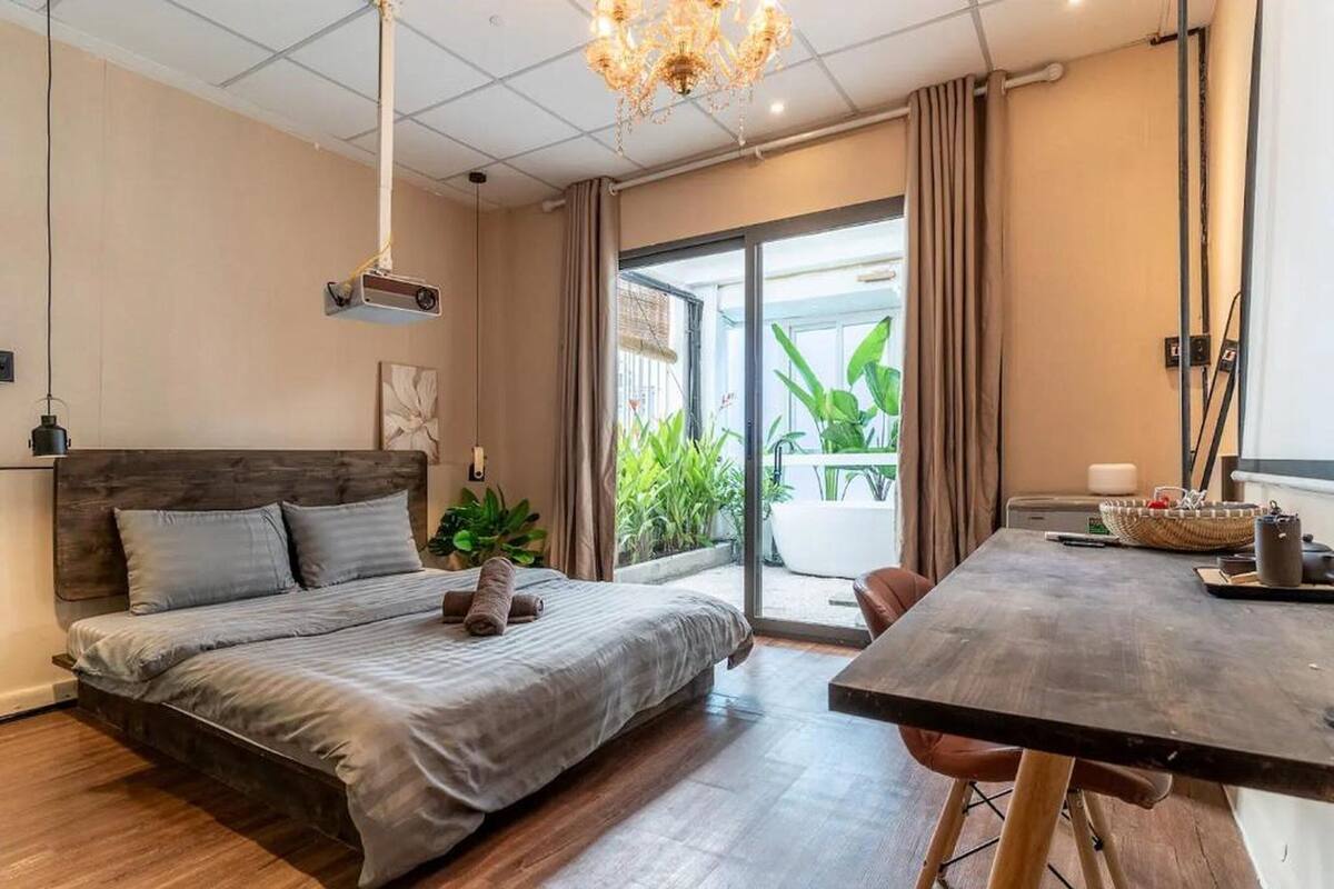 Ein modernes Schlafzimmer mit Bett, Esstisch und Blick ins Freie.